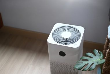 Portable air conditioner for camping in camper with house plant on the wooden floor.