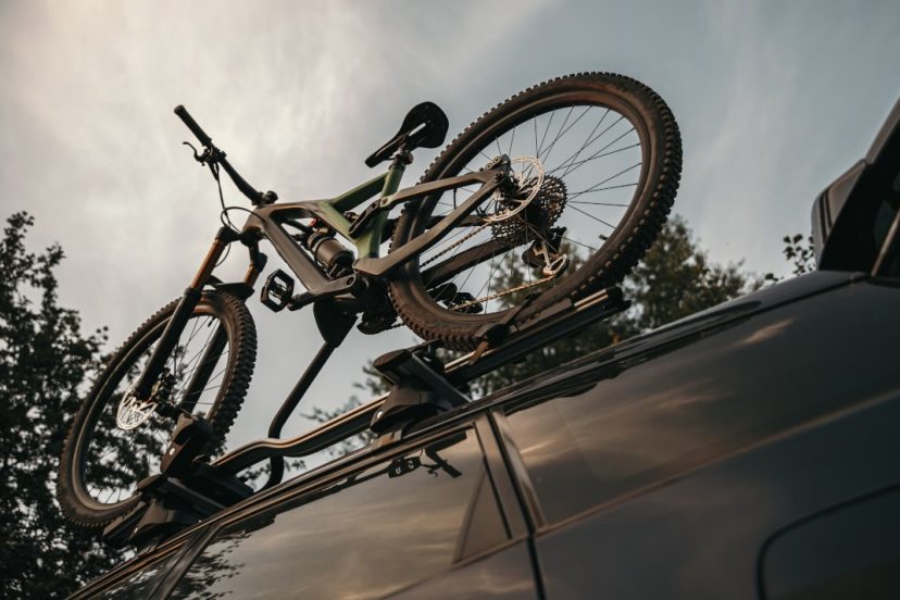 From below bicycle mounted on rack on roof of camper shell in countryside