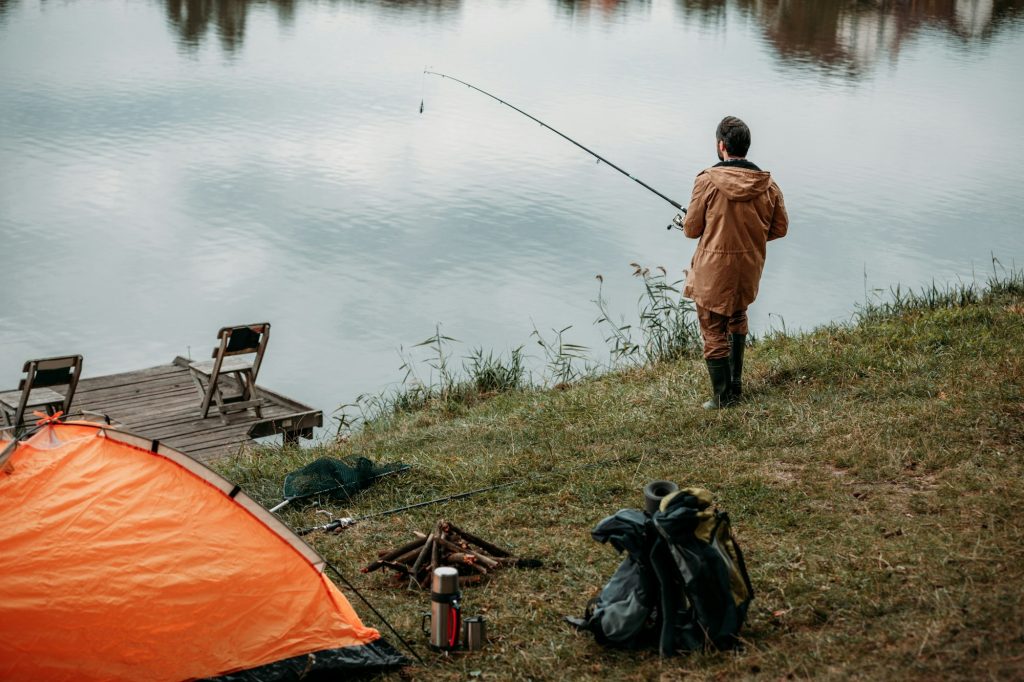 handsome fisherman fishing with rod at camping on lake