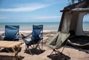Camping setup on the beach, Chairs, picnic table, and a tent with a campfire. Relish in family