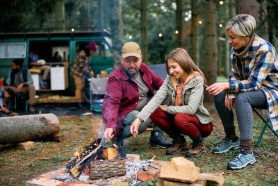 Happy family enjoying by bonfire at camping trailer park.