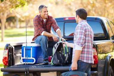 Two Men Unpacking Pick Up Truck On Camping Holiday