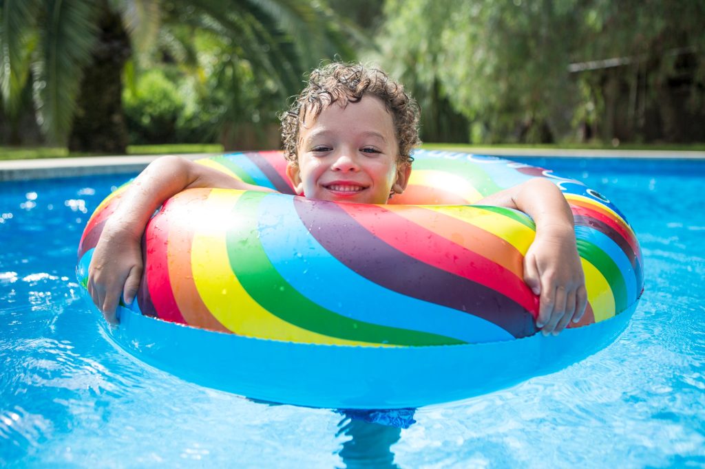 Boy with inflatable ring in outdoor swimming pool, portrait
