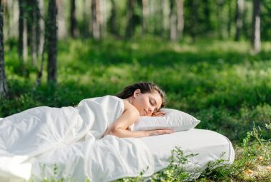 Woman sleeps on a mattress in the summer forest