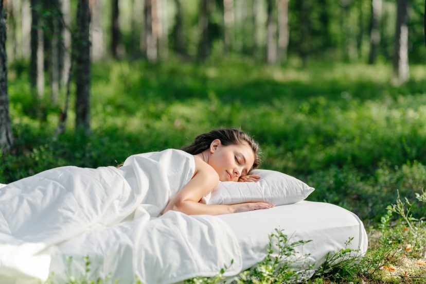 Woman sleeps on a mattress in the summer forest